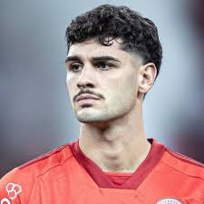 Atlético de Madrid Acerta Contratação de Johnny Cardoso do Betis Foto de Johnny Cardoso em ação com a camisa do Real Betis, disputando uma bola no meio-campo, com foco no jogador e o fundo do estádio desfocado.